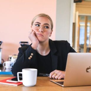 Junge Frau sitzt vor dem Laptop und hat Langeweile