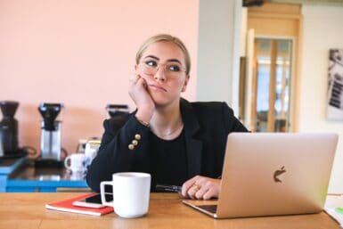 Junge Frau sitzt vor dem Laptop und hat Langeweile