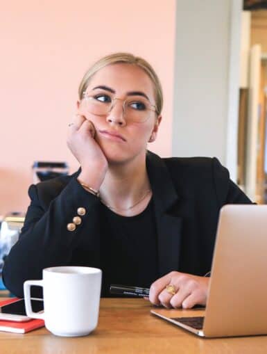 Junge Frau sitzt vor dem Laptop und hat Langeweile