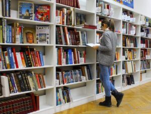 Frau liest stehend Buch in einer Bibliothek
