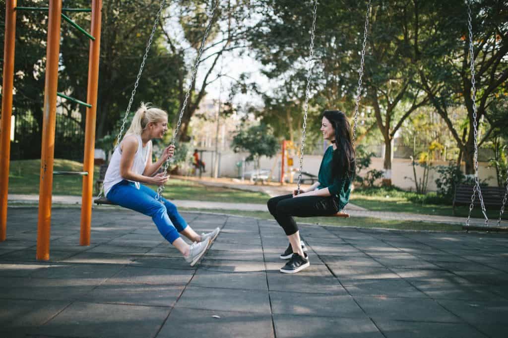 zwei junge Frauen schaukeln am Spielplatz