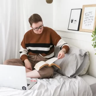 Junge Studentin lernt mit ihrem Laptop im Bett