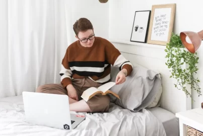 Junge Studentin lernt mit ihrem Laptop im Bett