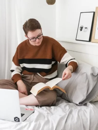 Junge Studentin lernt mit ihrem Laptop im Bett