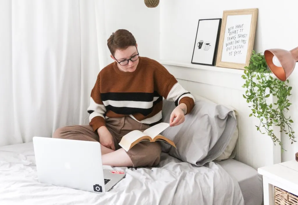 Junge Studentin lernt mit ihrem Laptop im Bett