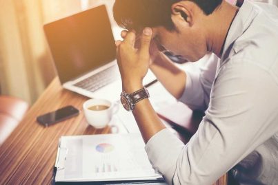 Mann am Arbeitsplatz im Büro. Er wirkt gestresst und nachdenklich.