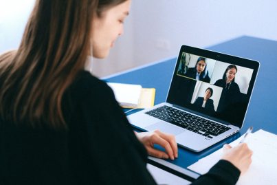Eine Studentin sitzt vor ihrem Laptop und ist in einem Online-Meetingroom mit drei weiteren Personen