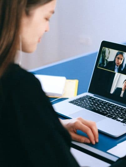 Eine Studentin sitzt vor ihrem Laptop und ist in einem Online-Meetingroom mit drei weiteren Personen