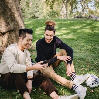 Zwei Studenten die auf ein Smartphone schauen und dabei lächeln