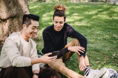 Zwei Studenten die auf ein Smartphone schauen und dabei lächeln