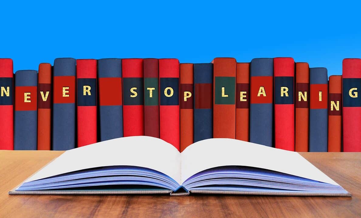 Aneinandergereihte Bücher mit den Initialen „NEVER STOP LEARNING“ und ein aufgeschlagenes Buch