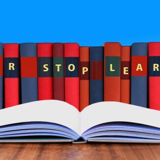 Aneinandergereihte Bücher mit den Initialen „NEVER STOP LEARNING“ und ein aufgeschlagenes Buch