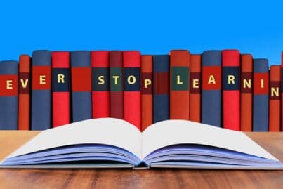 Aneinandergereihte Bücher mit den Initialen „NEVER STOP LEARNING“ und ein aufgeschlagenes Buch