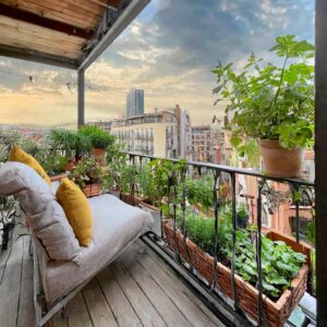 Ein Balkon in der Stadt. Mit Beeten und frischen Kräutern und Gemüse und Blick über die Dächer.