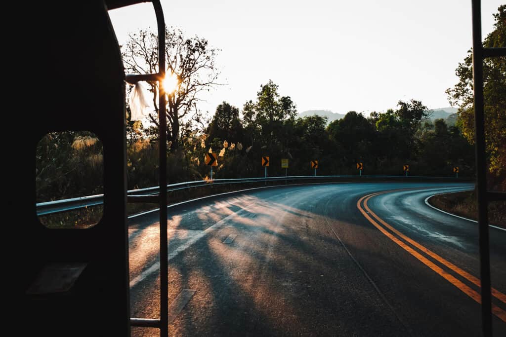 Foto einer Landstraße aus einem Bus heraus mit Sonnenuntergang