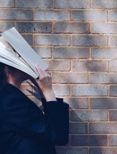 Bildungkarenz Studium - Frau schlägt Buch über Kopf