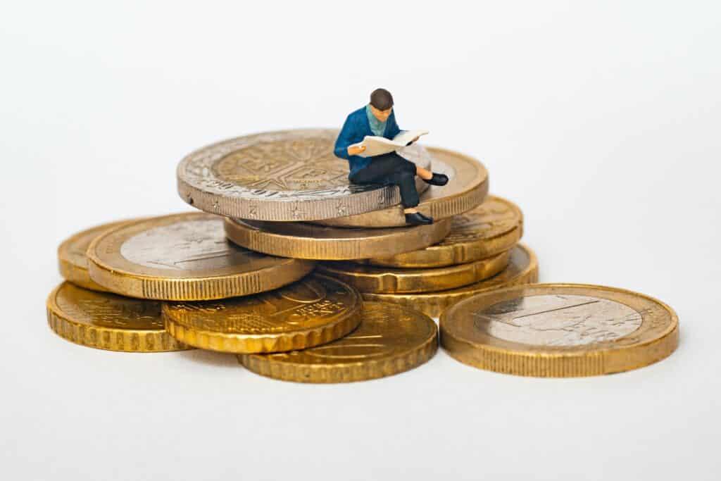 Bildungskarenz Studium - Figur sitzt auf Euromünzen
