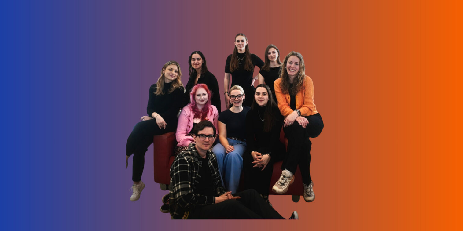 Das neue SOFA Team 2025 auf einem roten Sofa. Im Hintergrund sind die Farben der CI zu erkennen: blau und orange.