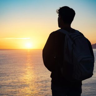 Bild eines Studenten vor einem Sonnenuntergang am Meer / KI generiert mit Adobe Express