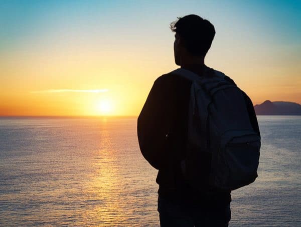 Bild eines Studenten vor einem Sonnenuntergang am Meer / KI generiert mit Adobe Express