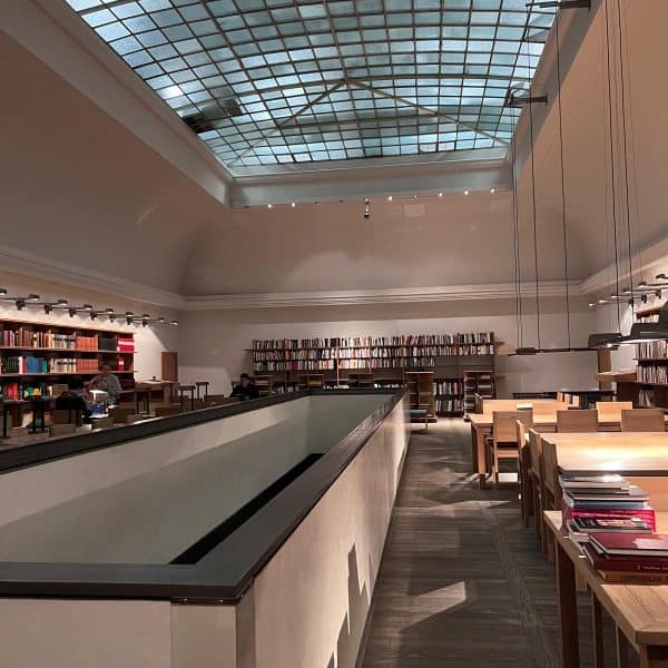 Zu sehen ist eine Bibliothek von innen. An den Wänden sind Bücher in Regalen einsortiert. Die Decke ist aus Glas. In Mitten der Bibliothek ist ein Geländer. Man kann hier in den unteren Stock sehen. (c) Shona Stern