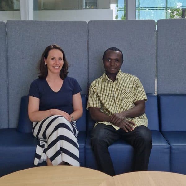 Zwei Personen sitzen auf einem Sofa in der FH-Aula. Sie lächeln in die Kamera.